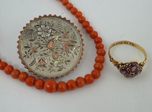 A Victorian 15ct gold and four stone garnet set ring, size L/M, a single strand coral bead necklace and a yellow and white metal brooch with aesthetic decoration. Condition - fair